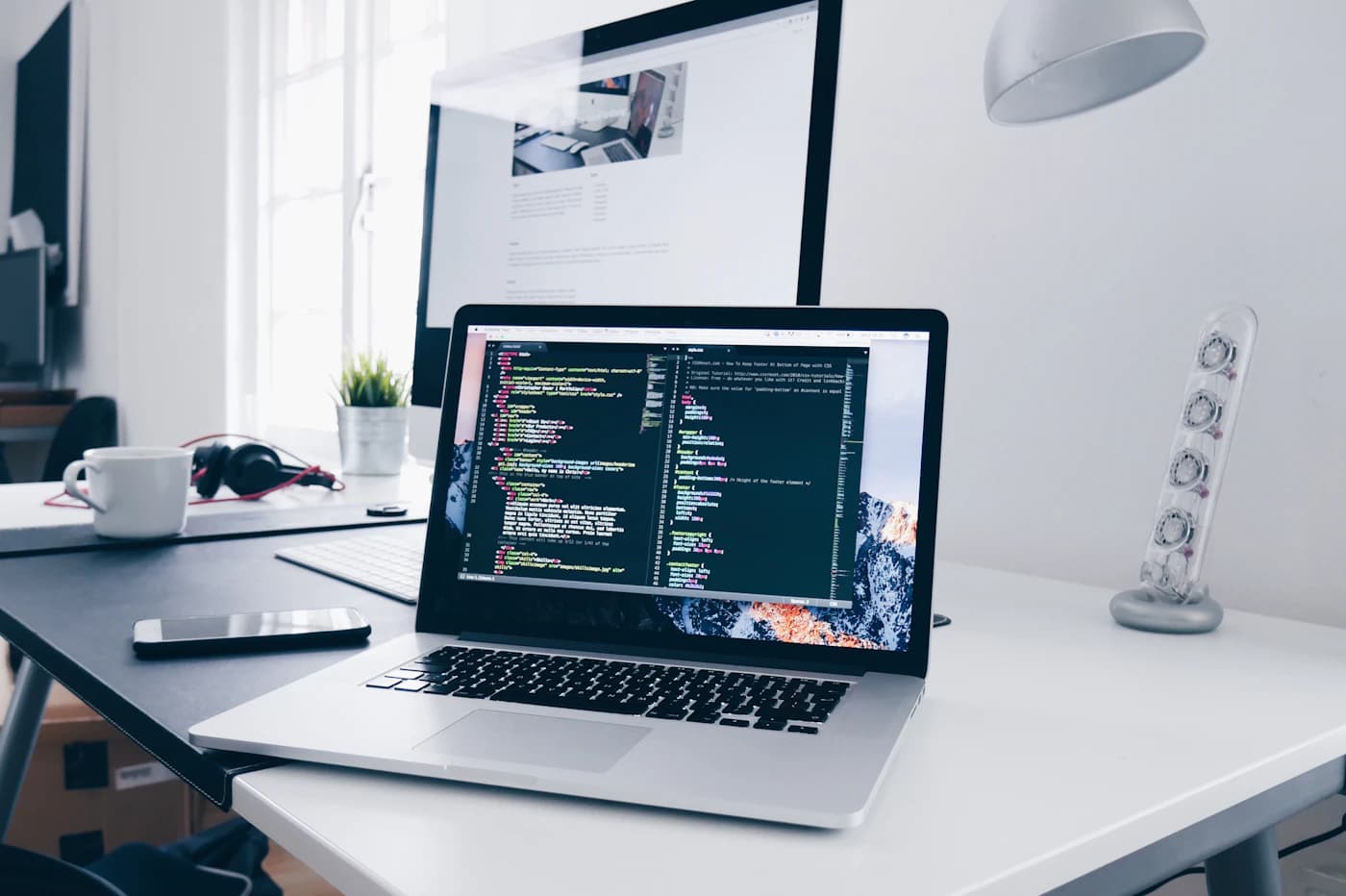 A laptop displaying source code on a developer's desk